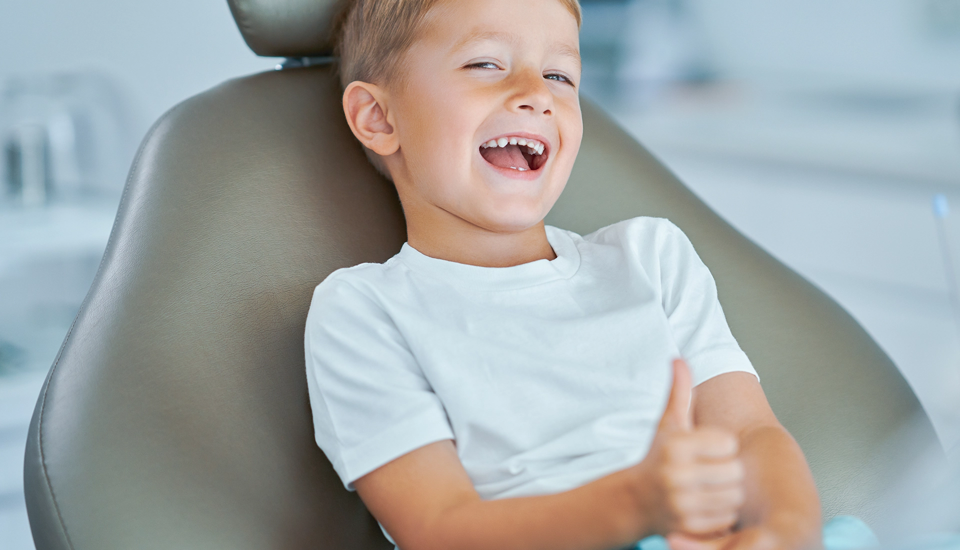 Niño sonriendo sentado en el sillón del dentista.