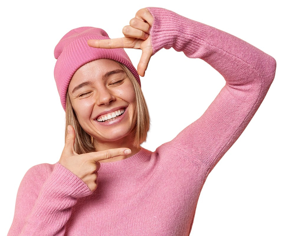 Una chica sonriendo enmarcando con sus manos la cara.
