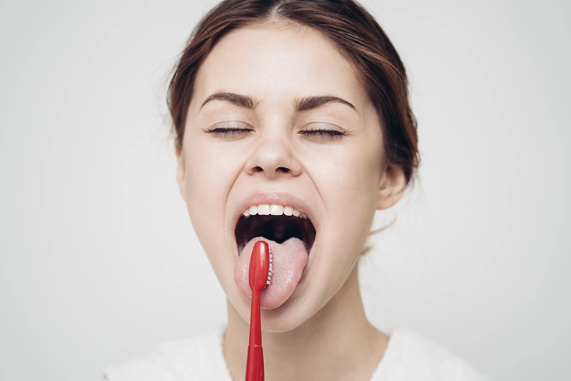 Una chica cepillándose la lengua.