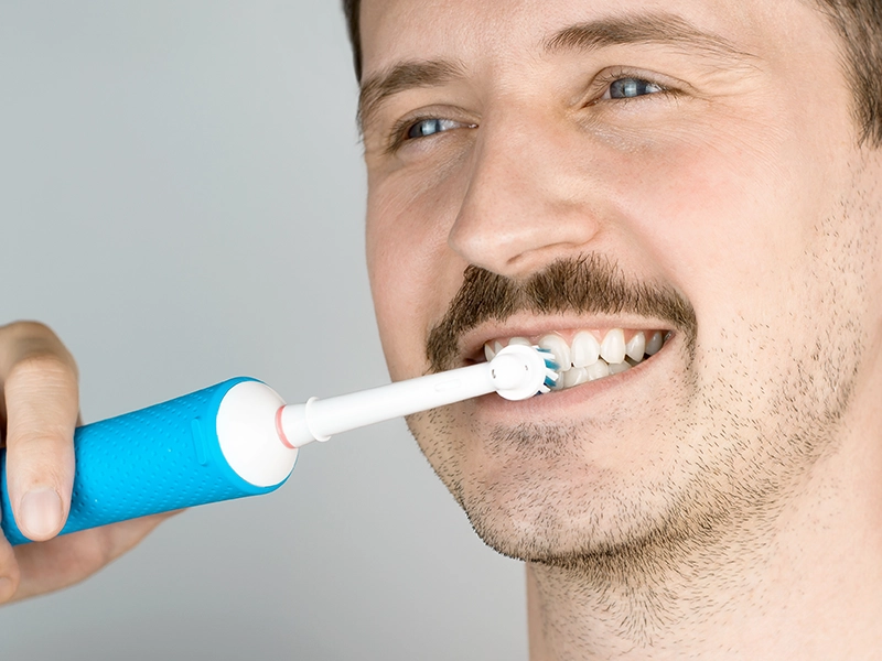 Un chico lavándose los dientes con cepillo eléctrico.