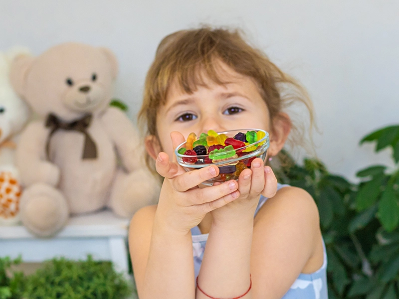 Una niña con gominolas en las manos.